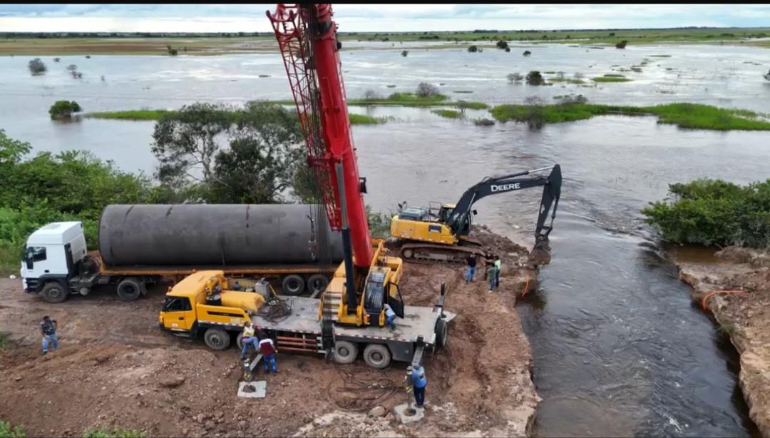 Grúa y excavadora instalando tubería en paso de agua