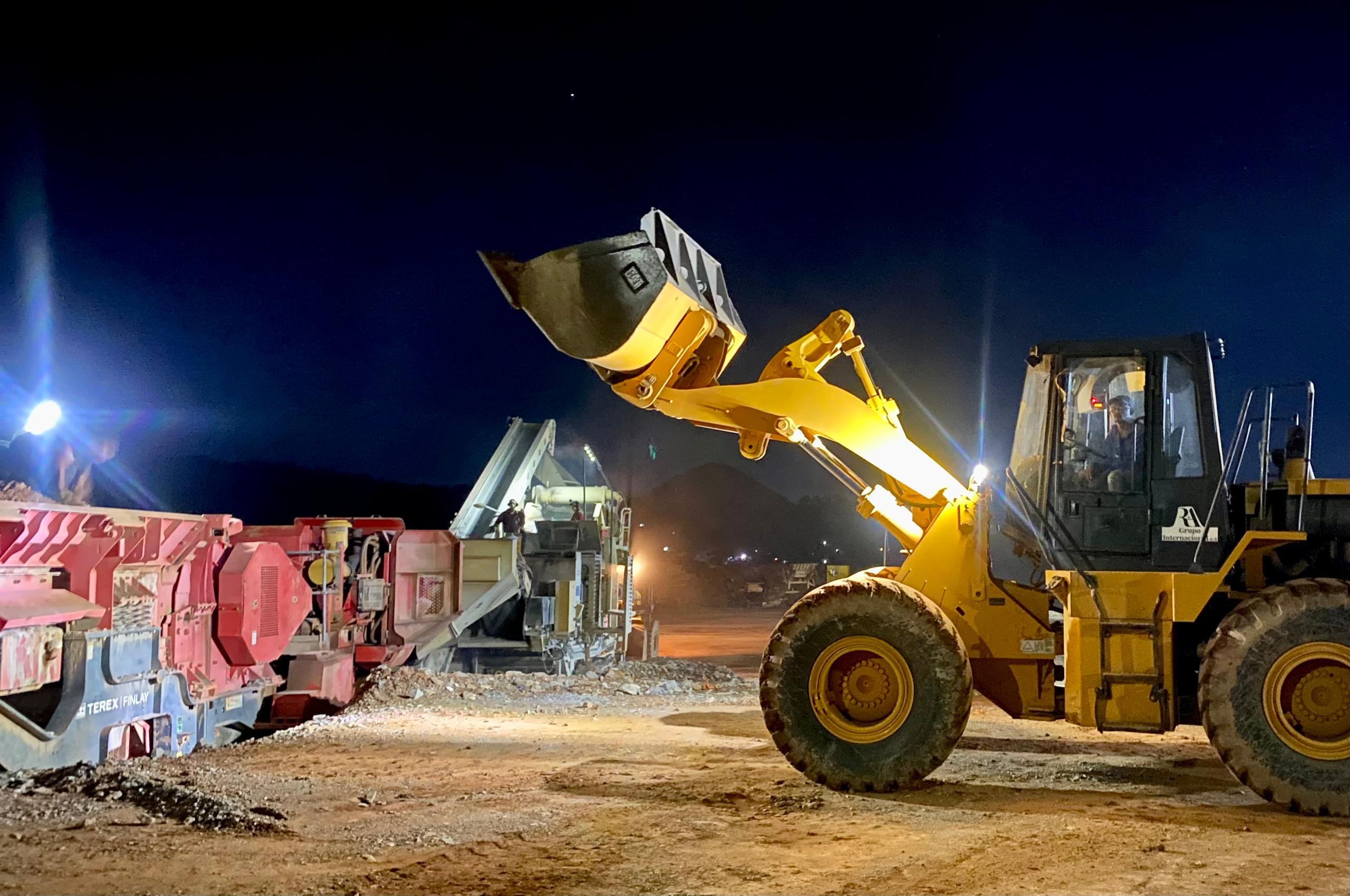 Cargador frontal alimentando planta de trituración de noche